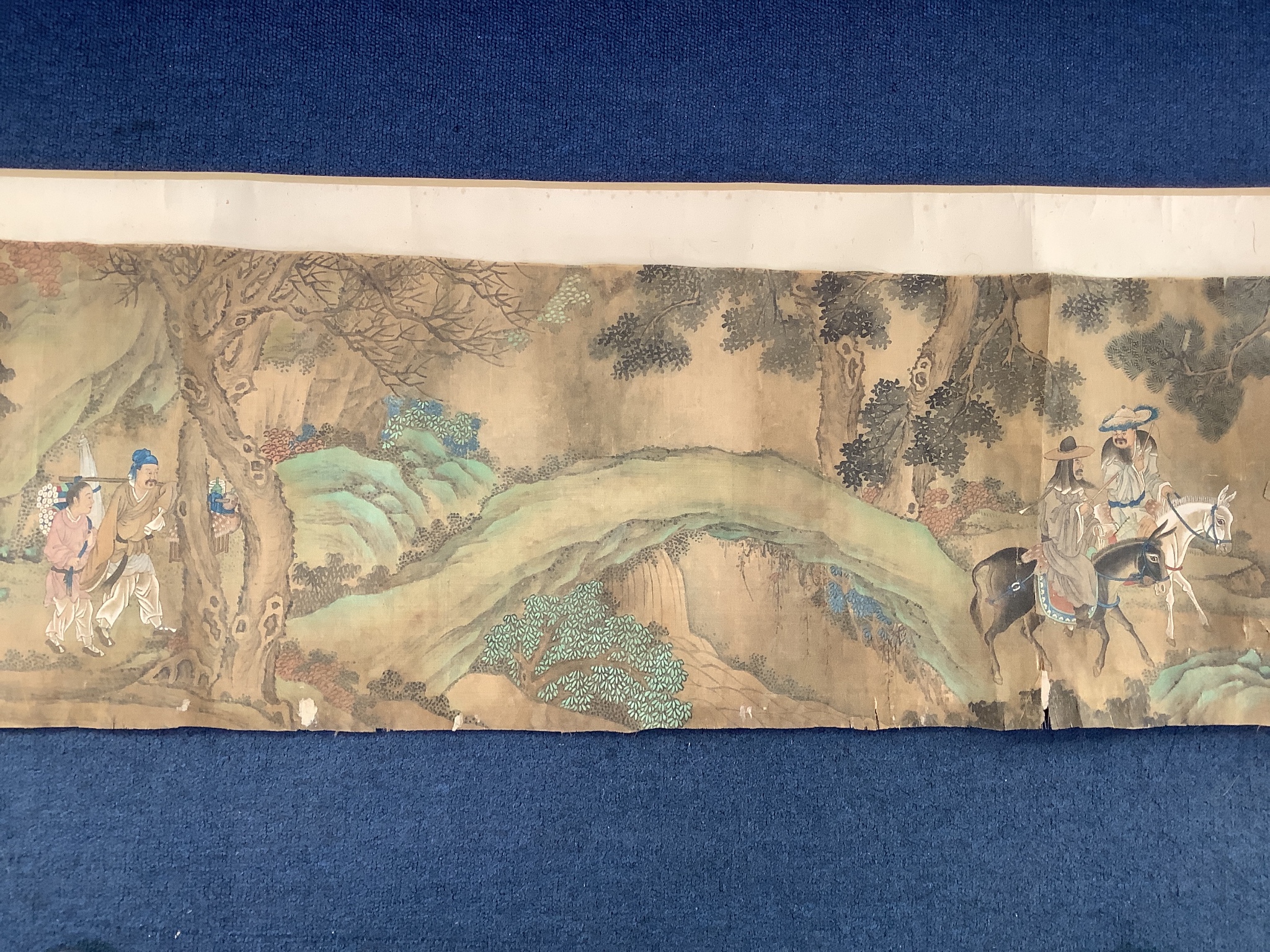 A 19th century Chinese hand scroll painting on silk of figures in a landscape, approximately 206 cm X 32.5 cm